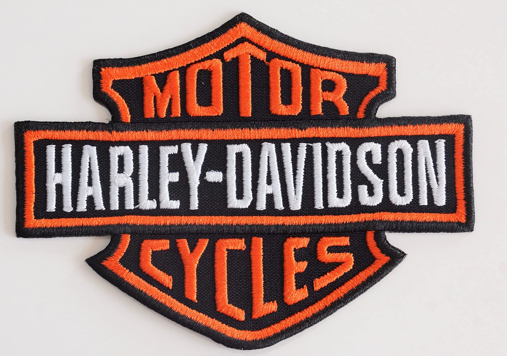 Logo Harley-Davidson Geborduurd logo van Harley-Davidson met de tekst "Motor Cycles" in zwart en oranje.